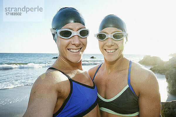Zwei Schwestern  Triathletinnen im Training in Badebekleidung  Badehauben und Schwimmbrillen.