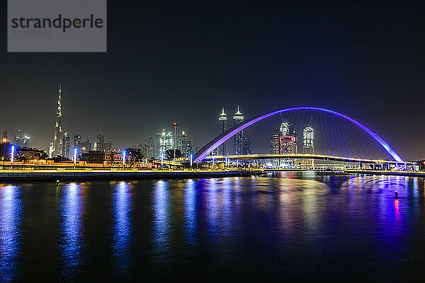 Nacht  Stadtbild von Dubai  hohe Gebäude und Uferpromenade  und Bogen über den Creek.