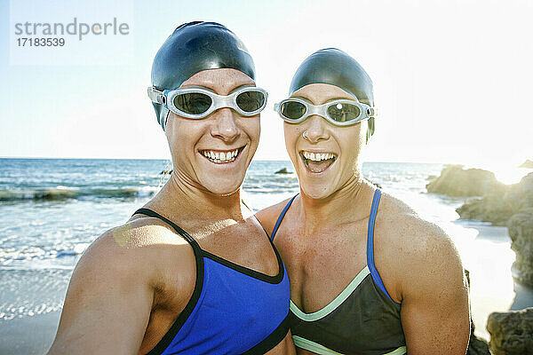 Zwei Schwestern  Triathletinnen im Training in Badekleidung  Badehauben und Schwimmbrillen.