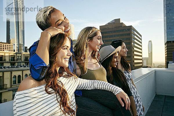 Eine Gruppe junger Frauen  die in der Abenddämmerung auf dem Dach einer Stadt feiern