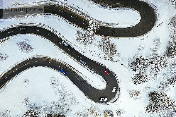 Luftaufnahme von Autos fahren auf Kurven der verschneiten Bergstraße im Winter  Schweiz  Europa