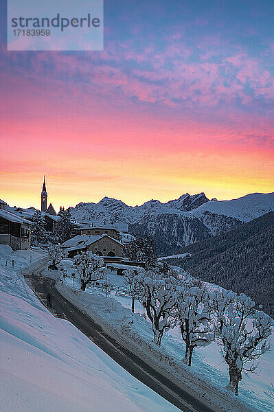 Sonnenaufgang auf leerer Straße in Richtung des Dorfes Guarda nach einem Winterschneefall  Unterengadin  Kanton Graubünden  Schweiz  Europa