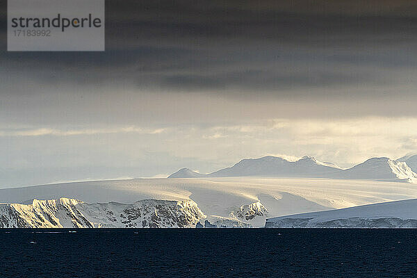 Sonnenaufgang über schneebedeckten Bergen und Gezeitengletschern in Mikkelsen Harbor  Trinity Island  Antarktis  Polarregionen