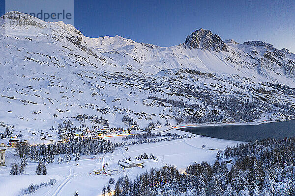 Dämmerung über dem verschneiten Dorf Maloja am Ufer des Silser Sees  Bergell  Engadin  Kanton Graubünden  Schweiz  Europa