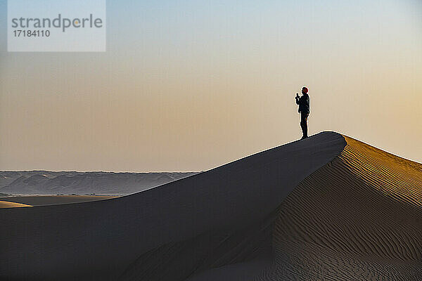 Mann wandert durch die Sanddünen  Dirkou  Djado Plateau  Sahara  Niger  Afrika