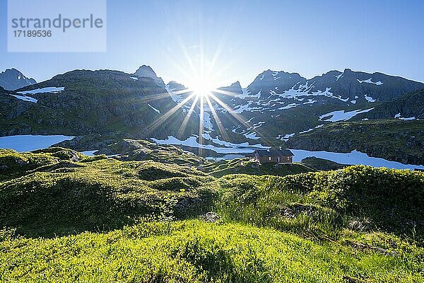 Sonne scheint auf Berge mit Schnee  Bergkette an der Berghütte Trollfjord Hytta  am Trollfjord  Lofoten  Nordland  Norwegen  Europa