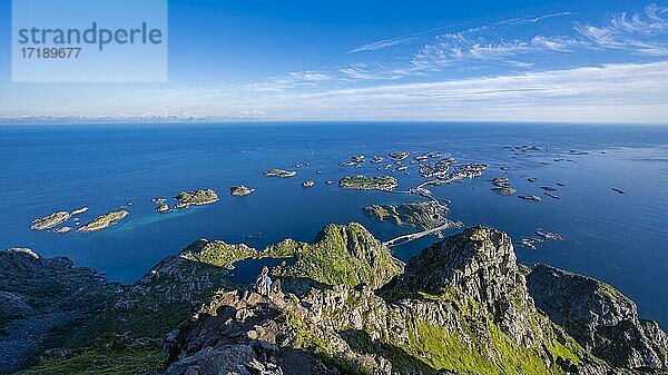 Kleine Felsinseln im Meer  Wanderin blickt vom Gipfel des Berges Festvågtind auf OrtHenningsvær  Vågan  Lofoten  Nordland  Norwegen  Europa