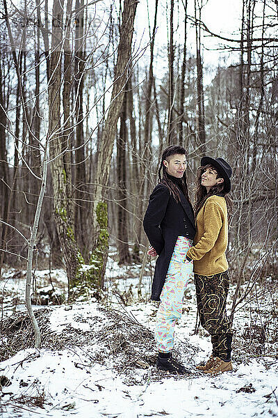 seltsames weibliches Paar lächelt zusammen im schneebedeckten Wald