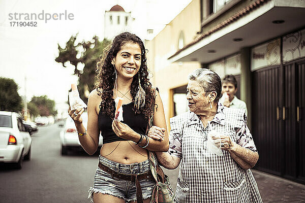 Junge attraktive Mexikanerin geht mit ihrer Großmutter über die örtliche Straße