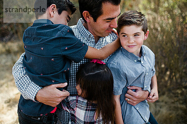 Vater hält drei Kinder auf einem Feld in San Diego
