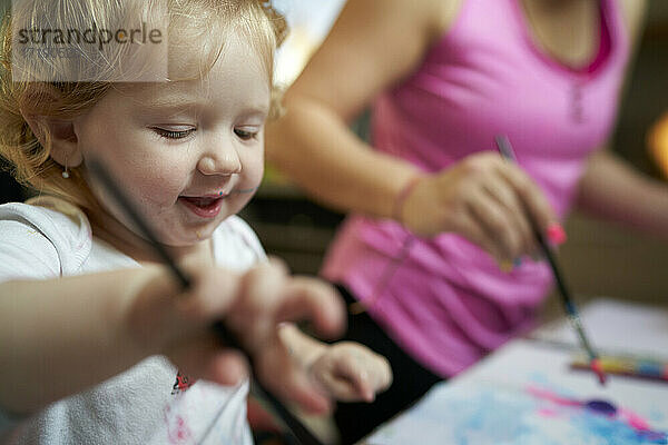 Glücklich lächelnd niedlichen kleinen Mädchen malen mit Pinsel