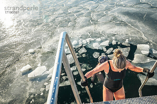 Zwei Winterbader schwimmen mit Eisbrocken an einem sonnigen Tag in Dänemark