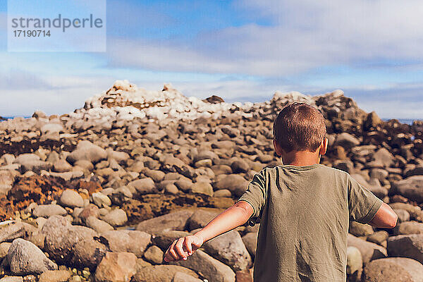 Ein Junge klettert auf einen felsigen Berg - mit dem Rücken zur Kamera.