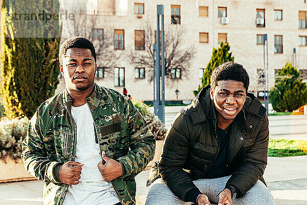 Porträt von zwei afroamerikanischen Freunden  die lächeln und sich in einem städtischen Raum amüsieren.