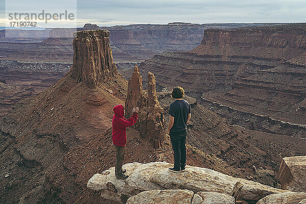 Männliche Freunde stehen am Rand eines Gipfels im Canyonlands National Park