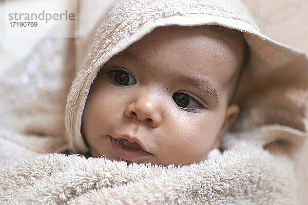 Ein hübsches Baby in ein Handtuch gewickelt  das sich in der Badewanne umsieht