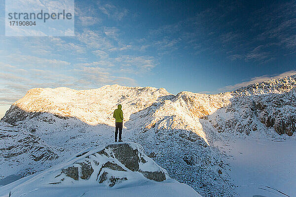 Mann steht auf einem felsigen Bergkamm  Blick auf eine malerische Bergkette