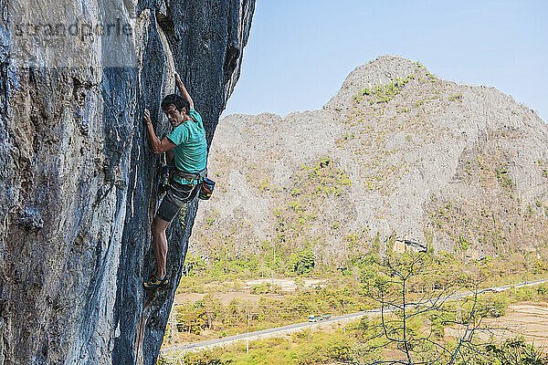 Mann klettert auf Kalksteinfelsen in Laos