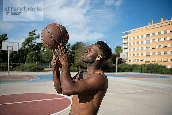 Afroamerikanischer Basketballspieler macht Trick mit Ball