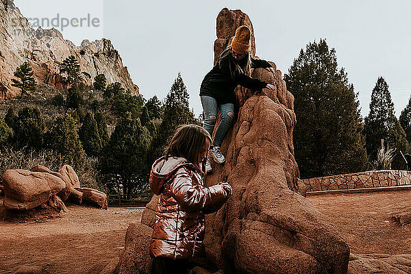 Zwei Mädchen klettern an einem sonnigen Tag auf eine Felsformation