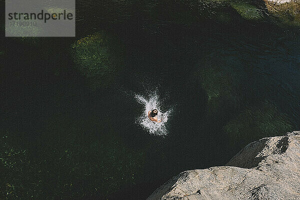 Junge schafft einen perfekten Spritzer im dunklen Wasser des Yuba River