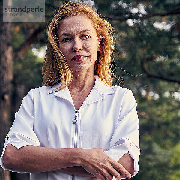 Porträt einer selbstbewusst im Park stehenden Heilpraktikerin