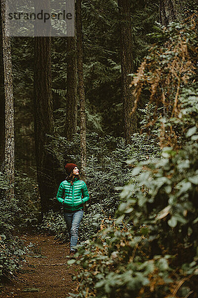 Eine junge Frau wandert allein in einem dichten und grünen Wald im Nordwesten