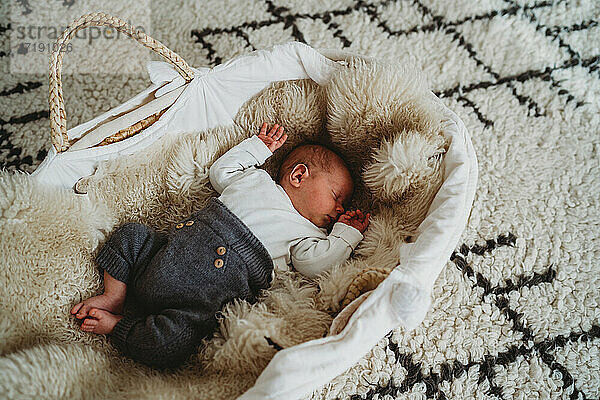 Adorable weißen neugeborenen Baby schlafen in Moses Korb mit gemütlichen Teppich