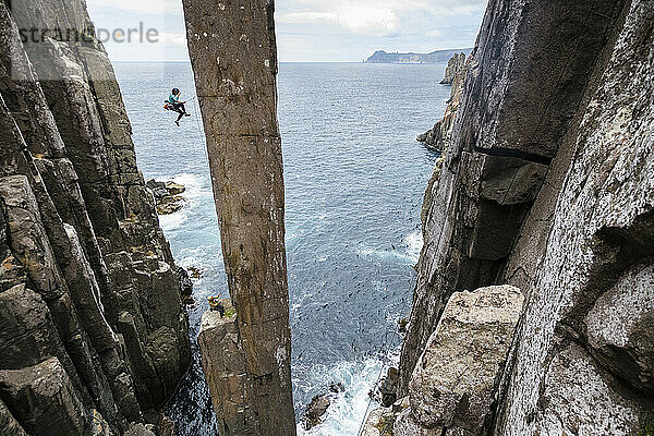 Eine Bergsteigerin stürzt beim Versuch  den Totem Pole zu erklimmen  einen aus dem Meer ragenden Felsvorsprung in Cape Hauy  Tasman National Park  Tasmanien  Australien.