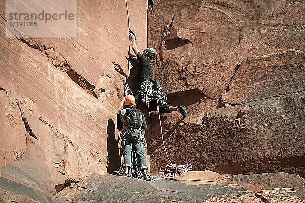 Männliche Freunde beim Klettern auf Felsformationen im Canyonlands National Park