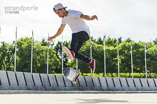 Junger Skateboarder macht einen Flip-Trick auf dem Boden