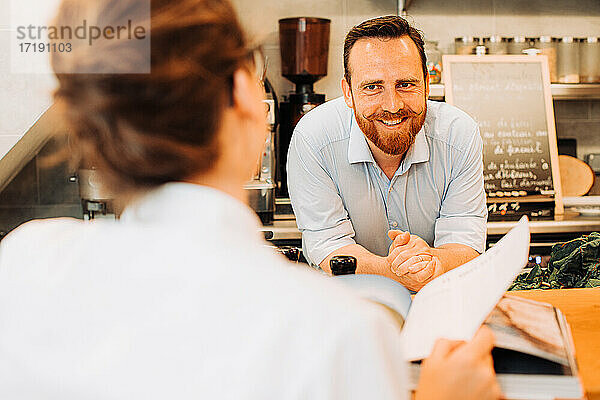 Lebensstil im Restaurant. Männlicher Koch am Bartresen lächelt den Kunden an