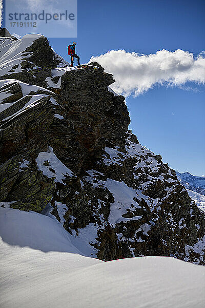 Ein Mann besteigt an einem sonnigen Tag einen verschneiten Berg in Devero  Italien.