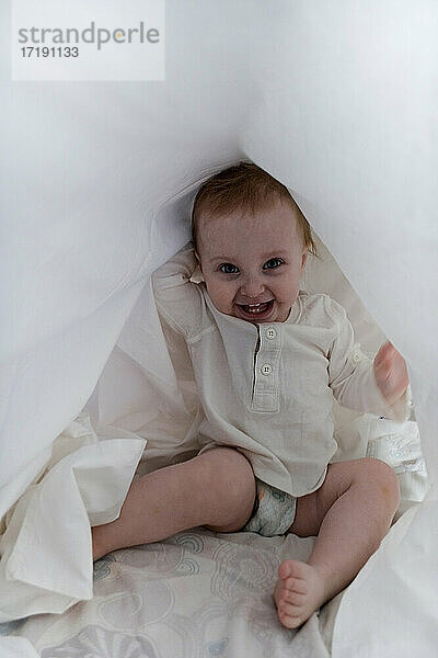Baby Girl versteckt sich unter dem Laken
