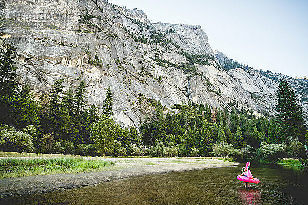 Weitwinkelaufnahme eines Mädchens in einem Flamingo-Floatie vor der Kulisse des Yosemite