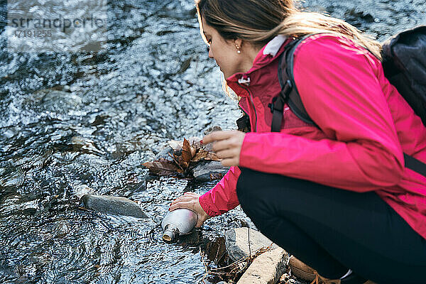 Wanderer Frau nimmt Wasser im Fluss nach dem Wandern. Glückliches Mädchen lächelnd genießen im Freien Sommer Trekking Urlaub.