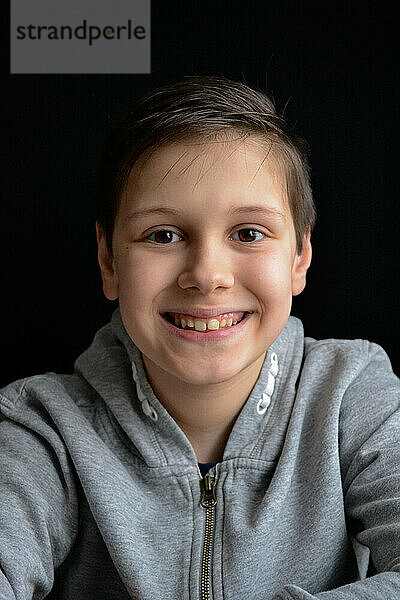 Porträt eines lächelnden Jungen vor einem schwarzen Hintergrund