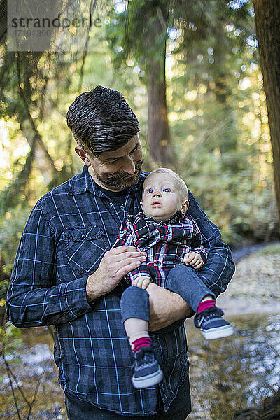 Vater hält seinen kleinen Sohn im Arm und genießt die Zeit mit ihm im Freien.