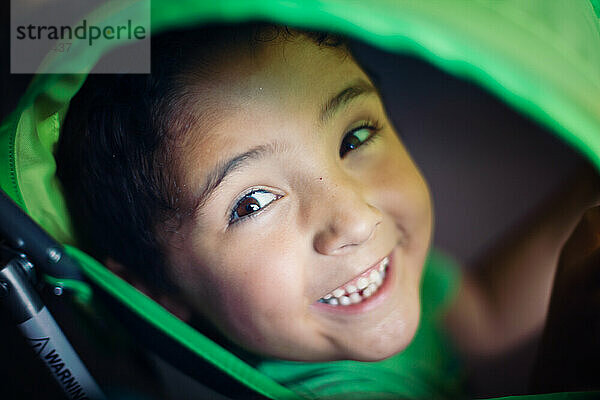 Junge schaut durch einen grünen Kinderwagen