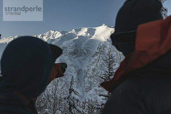 Menschen mit Blick auf schneebedeckte Berge im Urlaub