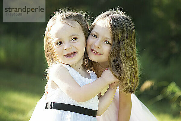 Zwei glückliche süße kleine Mädchen in Osterkleidern im Freien.