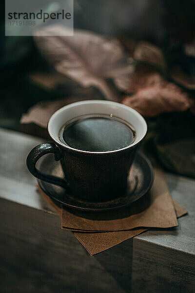 Warmer schwarzer Kaffee mit üppigem Hintergrund
