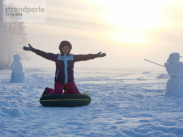 Glückliches Mädchen genießt Winteraktivität auf gefrorenem See und Winterwald