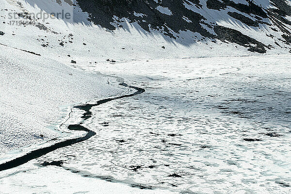 Gefrorener See mit Eis und verschneiten Bergen im Frühling bei einer Wanderung im Freien
