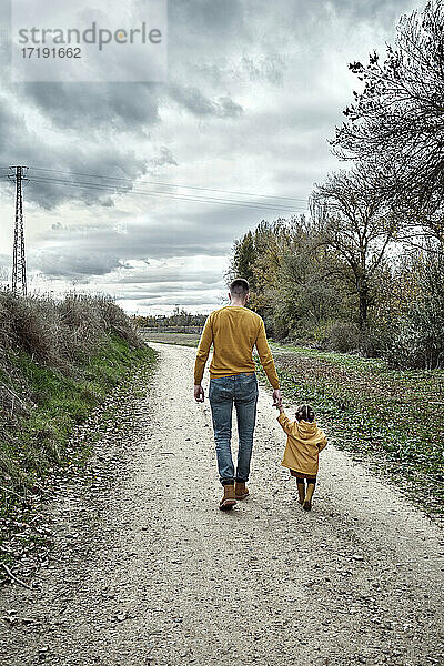 Ein zweijähriges Mädchen geht mit ihrem Vater spazieren