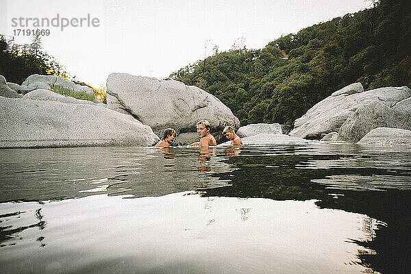 Drei Freunde liegen in der Abenddämmerung in einem Wasserbecken