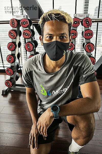 Fitness-Trainer demonstriert Sicherheit mit Maske und sozialer Distanzierung