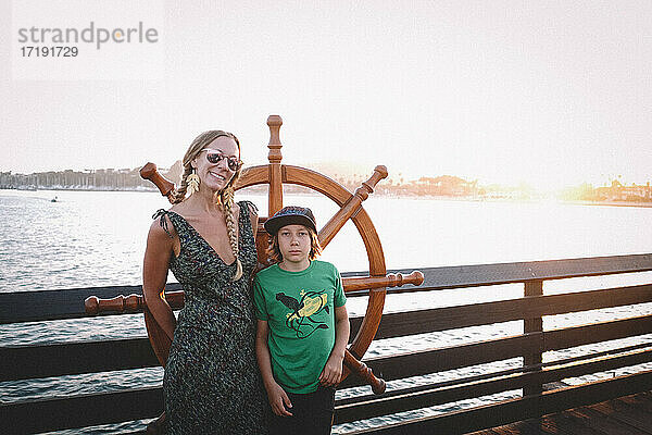 Mutter und Sohn stehen bei Sonnenuntergang neben einem Steuerrad auf einem Dock in Santa Barbara