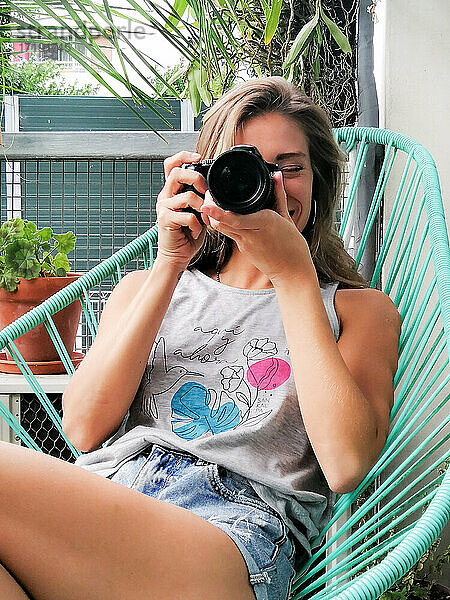 Junge Frau beim Fotografieren auf einem Balkon