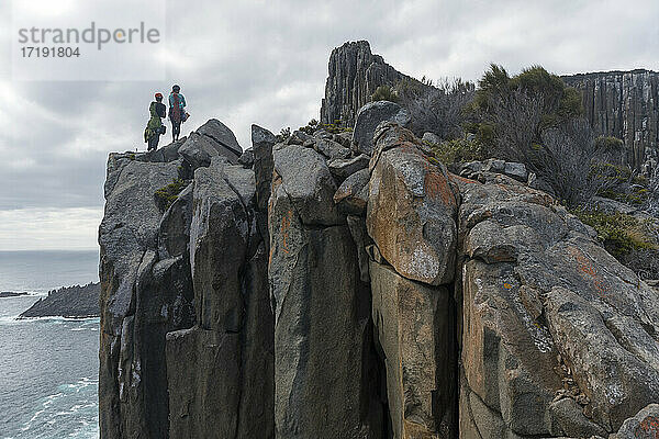 Ein Abenteurerpaar  bewaffnet mit Seilen und Kletterausrüstung  sucht seine nächste Herausforderung beim Klettern an den Meeresklippen von Cape Raoul  Tasmanien  Australien.